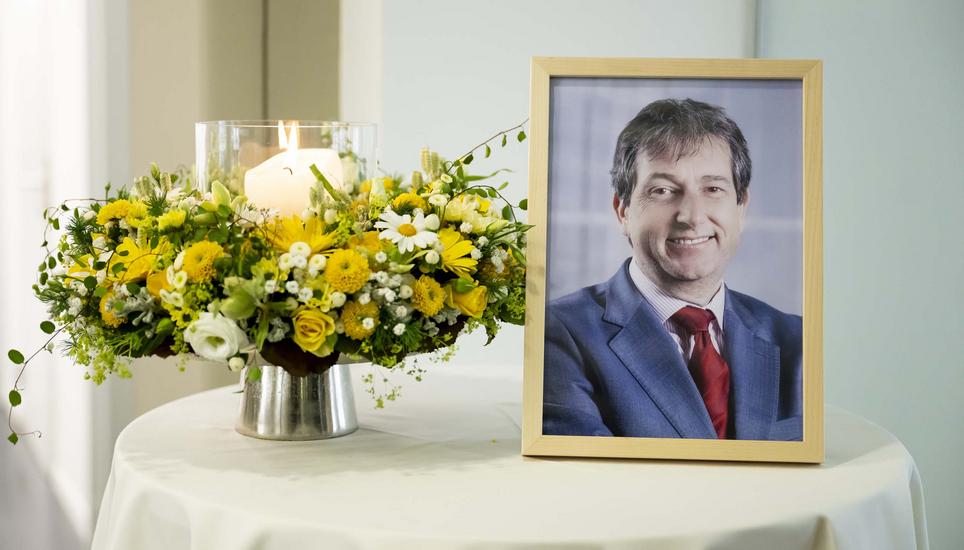 Ein Foto des Bundesratssprechers und Vizekanzlers Andre Simonazzi sowie ein Blumenstrauss und eine Kerze, fotografiert auf einem Tisch, vor den drei Pressekonferenzen des Bundesrates, am Mittwoch, 15. Mai 2024, im Medienzentrum Bundeshaus in Bern. Der lan