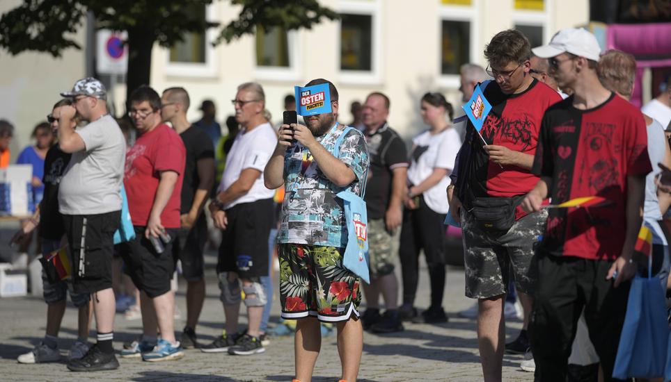 Supporters of the far-right Alternative for Germany party, or AfD, hold small paper flags that read: "The East Does it", as they attend an election campaign rally of the party for upcoming state elections in Suhl, Germany, Tuesday, Aug. 13, 2024. In the f