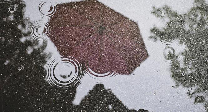 Ein knallig pinker Regenschirm spiegelt sich in einer Pfuetze auf dem grauen Asphalt. Wer an diesem regnerischen Tag vor die Tuer geht schuetzt sich mit einem Schirm. Wann kommt die Sonne wieder , am Dienstag, 21 Mai 2024. (Melanie Duchene / Schaffhauser 